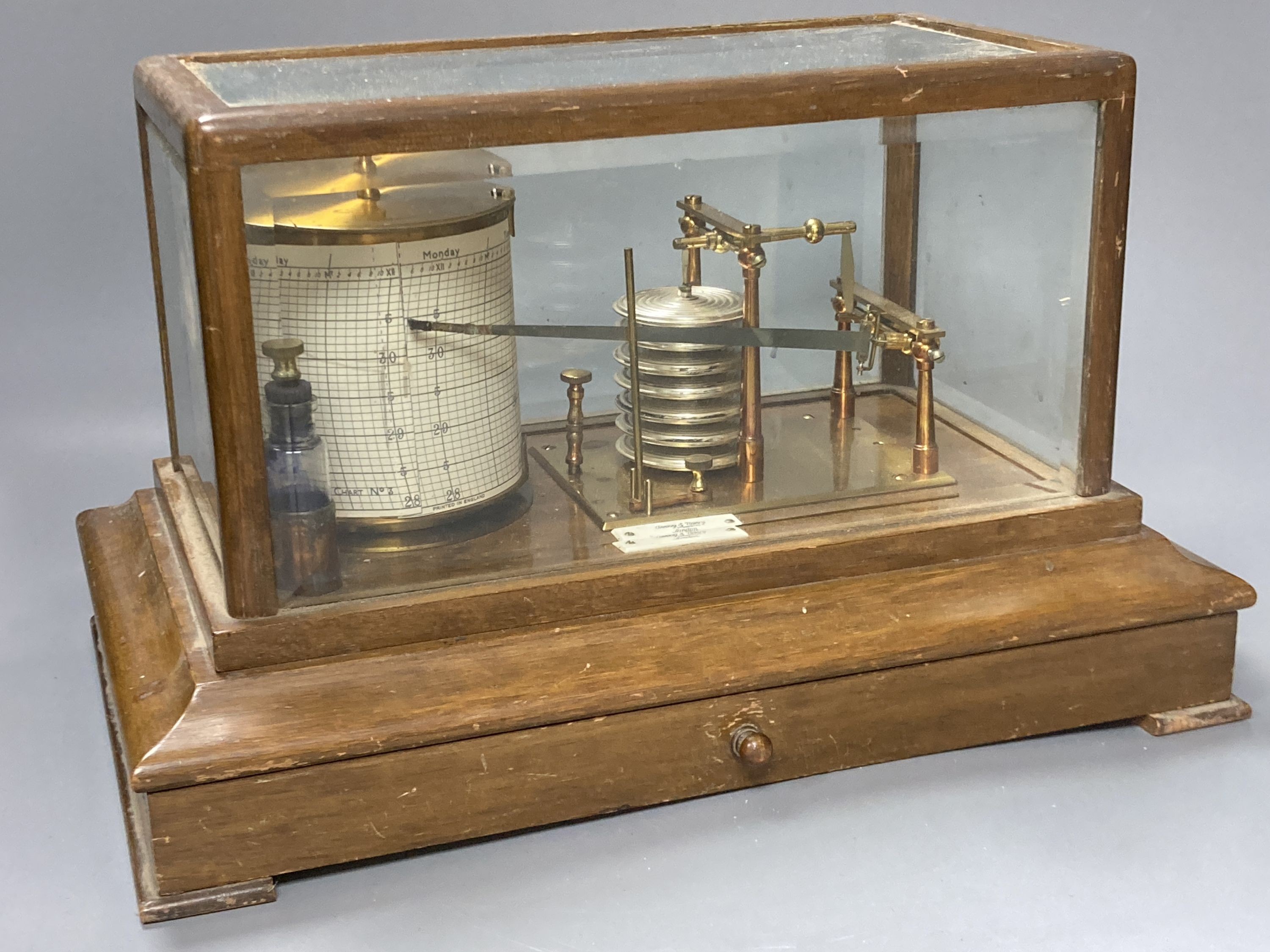 An Edwardian oak barograph retailed by Army & Navy stores ltd. with ink and spare sheets.